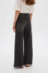 Pantalón jean gris de tiro alto, corte ancho (wide leg) con diseño de paneles tipo patchwork y terminación desmechada en el dobladillo.