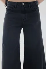 Jean de tiro medio con diseño de piernas anchas, color negro con efecto gastado, cuatro bolsillos tradicionales y cierre frontal con botón y cremallera.