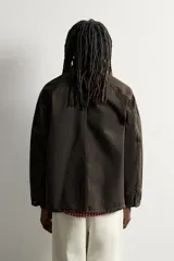 Chaqueta relaxed fit marrón oscuro confeccionada en tejido de algodón. Presenta cuello solapa, manga larga ranglán, bolsillos frontales de plastrón, efecto lavado y cierre frontal con botonadura. Colección especial Aaron Levine x Zara.