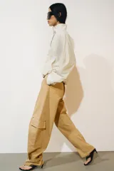 Chaqueta de nylon color crudo, con cuello alto, mangas largas, bolsillos delanteros, bajo abullonado con elástico y cierre frontal con botones forrados.