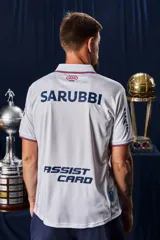 Camiseta de fútbol Umbro del Club Nacional de Football, modelo Home 2026. Diseño blanco con cuello en V, detalles en azul y rojo en el cuello y las mangas, y patrón en tejido jacquard. Incluye el logo de Umbro, el escudo del club y el sponsor antel en el pecho.