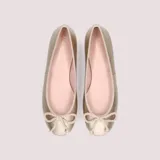 Bailarinas doradas de cuero con lazo decorativo en la puntera y plantilla de color rosa.