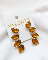 Aros colgantes con tres piedras facetadas color ámbar engarzadas en metal plateado.