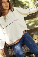 Buzo de algodón color crema con cuello redondo, puños y ruedo en color tostado. Presenta una línea horizontal marrón y el texto 'azu' bordado en color rosado en el pecho.