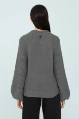 Sweater gris de tejido de punto grueso, con cuello redondo y mangas ranglán abuchonadas.