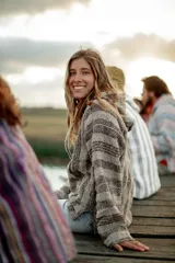 Buzo tejido con capucha, de corte holgado y diseño a rayas horizontales en tonos beige y marrón.