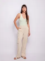 Pantalón cargo de color beige, con bolsillos laterales tipo cargo y bolsillos frontales. Presenta una costura central en las piernas, cierre frontal con botón y cremallera, y elástico en la parte posterior de la cintura para un ajuste cómodo.