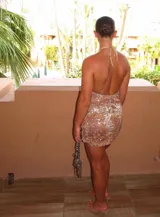 Vestido corto ajustado con escote profundo en V y cuello halter, cubierto completamente de lentejuelas con patrón moteado en tonos marrones, naranjas y blancos.