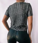 Remera de fiesta con lentejuelas plateadas formando un patrón de rombos. Incluye top negro de breteles finos para usar debajo.