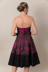 Vestido strapless negro con estampado de hojas fucsias y guarda calada negra en el bajo.