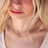 Collar dorado con cadena fina y dijes colgantes en forma de triángulos pequeños.