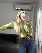 Sweater de tejido de punto con diseño de rombos en tonos verde oliva, verde oscuro y blanco. Presenta cuello redondo, mangas largas con puños acanalados y un corte holgado.