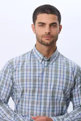 Camisa sport de manga larga con estampado de cuadros en tonos azules, grises y blancos. Presenta cuello con botones, cierre frontal abotonado y un bolsillo pequeño en el pecho.