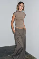 Top negro de tejido de punto, corte ajustado, con cuello alto y mangas sisa caídas.