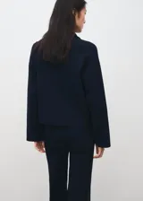 Jersey Cosmus de punto azul marino con cuello alto y cierre frontal de cremallera corta, manga larga y detalles de ribetes claros en las costuras.