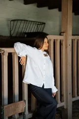 Camisa de lino de corte relajado y silueta holgada, con cuello clásico y cierre frontal de botones forrados en lino a rayas. Presenta mangas largas con puños amplios.