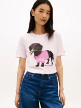 Remera de manga corta color rosado de Tommy Hilfiger, con cuello redondo y diseño casual. En el centro del pecho cuenta con un gráfico bordado de un perro salchicha con un suéter a cuadros rosado y blanco, y flores en la boca.