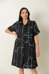 Camisa larga negra con estampado de líneas geométricas en gris, de manga corta y dos bolsillos delanteros.