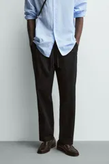 Pantalón de corte relajado confeccionado en una mezcla de algodón y lino. Presenta cintura elástica con cordón ajustable, bolsillos laterales y bolsillos traseros de vivo.