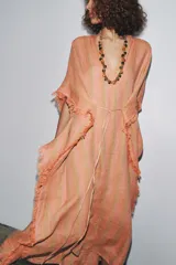 Vestido largo tipo kaftán confeccionado en lino a rayas verticales en tonos naranja y verde. Tiene cuello redondo con escote en V, mangas cortas amplias, acabado deshilachado y cinturón de cordón en el mismo tejido.