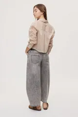 Jean de tiro medio y corte barrel con pierna amplia y ligeramente curva, estilo de cinco bolsillos en denim negro lavado.