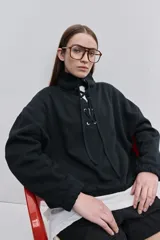 Buzo de algodón negro con calce relajado, cuello alto con cordones cruzados y ojales metálicos, bolsillos laterales y puños y ruedo elásticos.