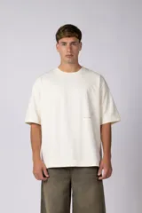 Remera de corte oversize en color crudo, con cuello redondo y mangas cortas. Presenta un pequeño estampado gráfico minimalista en el lado derecho del pecho.