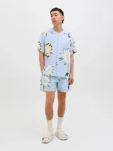 Short de baño de tiro medio con estampado floral en tonos claros sobre fondo celeste. Cuenta con cintura elástica con cordón ajustable, bolsillos laterales y un bolsillo trasero.