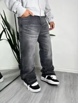 Jeans de corte flare y tiro medio, con efecto acid wash en tono gris oscuro y detalle de dobladillo deshilachado.