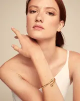 Pulsera rígida dorada con terminaciones redondeadas, de aleación de metales bañados en oro 18k con muelle interior.