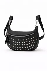 Cartera tipo bandolera de diseño semicircular, confeccionada en cuero sintético negro con tachas metálicas plateadas distribuidas por toda la superficie frontal. Cuenta con cierre superior metálico y correa ajustable.