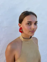 Aros tipo caravanas con diseño de flor irregular en color rojo vibrante y centro con detalle de pequeñas perlas.