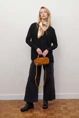 Sweater de tejido de punto color beige, con escote en V y mangas largas. Presenta un diseño básico y versátil de corte recto.