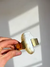 Brazalete rígido hecho a mano en bronce dorado con pieza irregular de nácar engarzada.