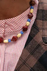 Collar corto compuesto por cuentas de cristal checo en tonos bordó, crema y azul, con diseño de formas geométricas y esféricas.