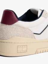 Zapatillas de corte bajo Tommy Jeans, confeccionadas en una combinación de cuero y ante en tonos blanco, beige y burdeos. Presentan suela cupsole de goma en color crema, cordones moteados y el logo de la marca en el lateral.
