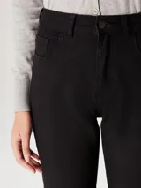 Pantalón de jean negro de corte skinny y cintura media, con cierre frontal y bolsillos laterales.