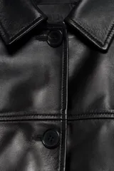 Cazadora de cuero 100% de color negro, con cuello de solapa, manga larga, bolsillos frontales de parche y cierre central con botones.