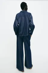 Pantalón de jean estilo wide leg en color azul oscuro, con cintura elástica y cordón ajustable. Presenta costuras verticales decorativas en el frente y bolsillos laterales.