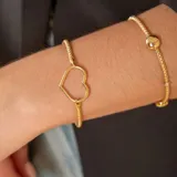 Pulsera de oro 18k compuesta por una cadena de malla y un dije central en forma de corazón, con diseño extensible.