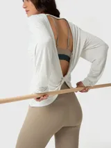 Polera de manga larga con espalda abierta y detalle de nudo en la parte inferior. Confeccionada en modal, presenta un diseño ligero y fluido ideal para actividades deportivas.