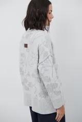 Buzo de tejido de punto con cuello redondo, mangas largas con puños acanalados y diseño estampado de flores en tonos rojos.