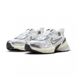 Championes Nike V2K Run de estilo retro-futurista, con diseño en capas de malla y material sintético en tonos beige y gris. Presenta una entresuela robusta con tecnología Cushlon y el logo de Nike en el lateral.