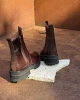 Botas de cuero con textura simil cocodrilo en color marrón, diseño de caña baja con cierre lateral y suela track negra de goma.