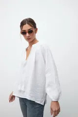 Camisa blanca de crepe con escote en V y mangas largas abullonadas.