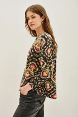 Sweater de punto con cuello redondo y manga larga, estampado en tonos oscuros con motivos geométricos y florales en rosa, amarillo y verde.