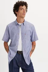 Camisa de manga corta Levi's en color azul con textura tipo chambray. Presenta cuello clásico, cierre frontal con botones y un bolsillo en el pecho con la etiqueta roja característica de la marca.