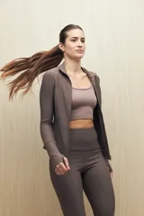 Campera deportiva de textura acanalada, color negro, con cierre frontal, cuello alto y mangas largas con orificio para el pulgar.