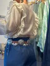 Cinturón marrón de cuero con hebilla plateada rectangular con diseño de flores y apliques metálicos circulares con diseño de flores.