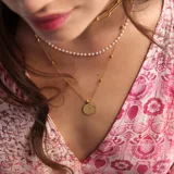 Collar triple dorado: cadena gargantilla de eslabones pequeños, cadenita media con perlas y cadena larga con dije circular de la Reina Isabel.